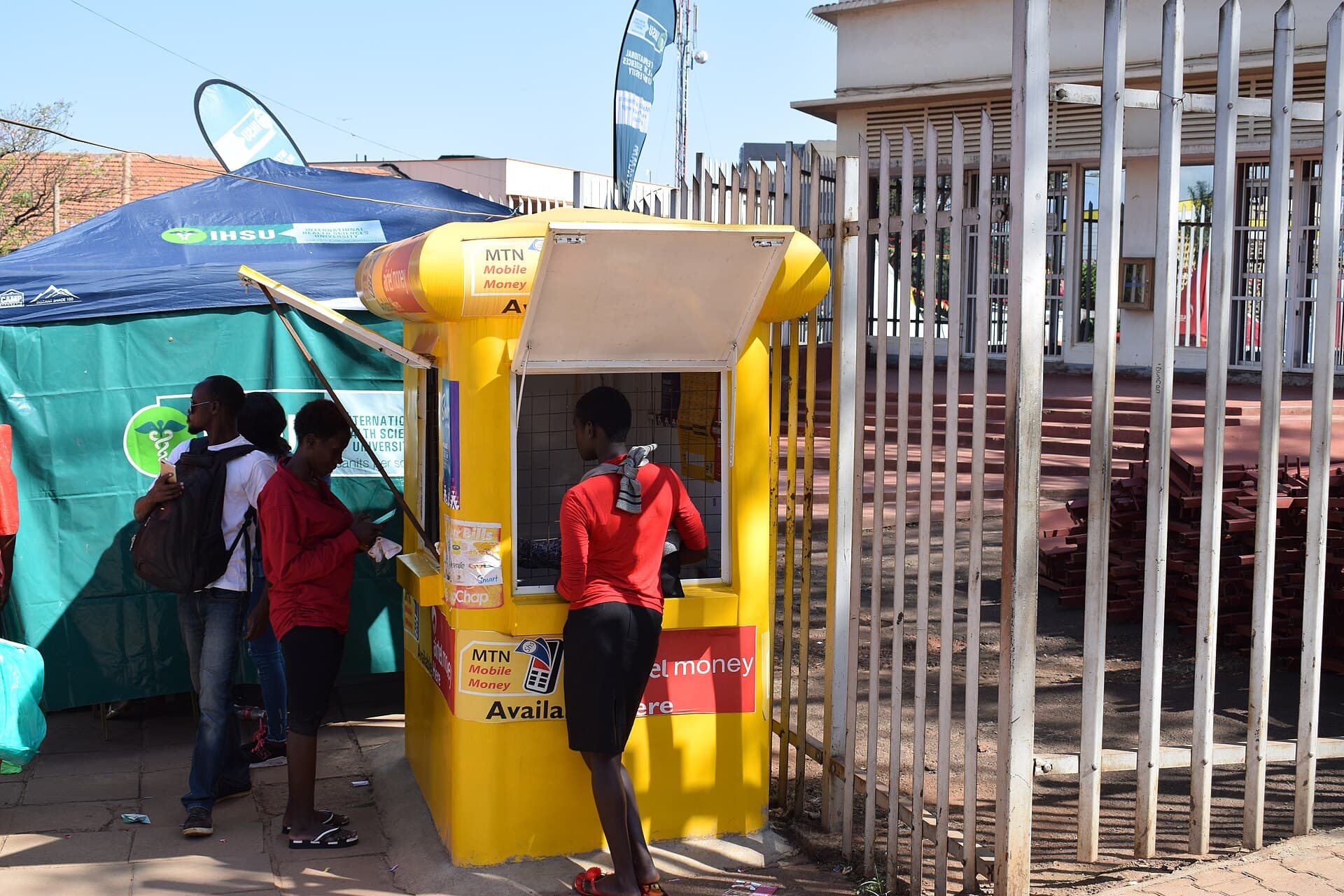 Kiosque Mobile Money aux couleurs MTN où des clients effectuent une opération